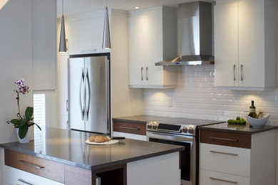 Inspiration for a large contemporary galley separate kitchen in Montreal with an undermount sink, flat-panel cabinets, white cabinets, solid surface benchtops, white splashback, subway tile splashback, stainless steel appliances, ceramic floors, with island and brown floor.