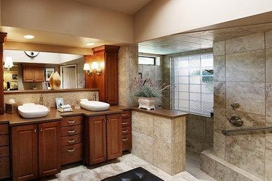 Inspiration for a mid-sized timeless master multicolored tile and porcelain tile porcelain tile doorless shower remodel in Burlington with a vessel sink, raised-panel cabinets, medium tone wood cabinets, solid surface countertops, a one-piece toilet and beige walls