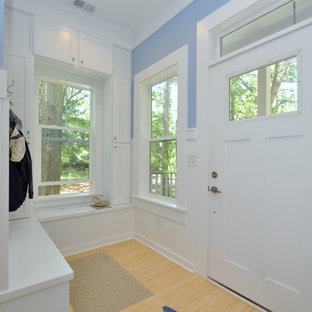 Idee per un piccolo ingresso con anticamera con pareti blu, pavimento in bambù, una porta singola e una porta bianca