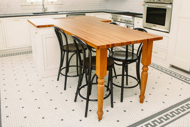 Example of a large trendy porcelain tile and white floor eat-in kitchen design in New Orleans with recessed-panel cabinets, white cabinets, wood countertops, stainless steel appliances, an island and brown countertops