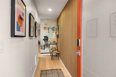 Hallway - small mid-century modern light wood floor, brown floor and wall paneling hallway idea in Seattle with white walls