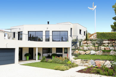 Réalisation d'une façade de maison blanche design à niveaux décalés avec un toit plat.