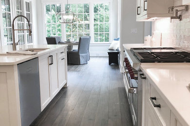 Inspiration for a modern dark wood floor and gray floor kitchen remodel in Atlanta with shaker cabinets, quartzite countertops, white backsplash, subway tile backsplash, stainless steel appliances, an island and white countertops
