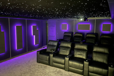 Photo of a medium sized traditional enclosed home cinema in Other with grey walls, carpet, a projector screen, grey floors and feature lighting.