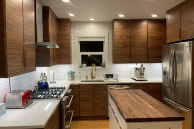 Example of a mid-sized transitional u-shaped kitchen design in Seattle with flat-panel cabinets, medium tone wood cabinets, quartz countertops, white backsplash, an island and white countertops