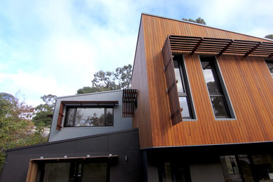 Inspiration for a mid-sized contemporary two-storey black house exterior in Adelaide with wood siding and a metal roof.
