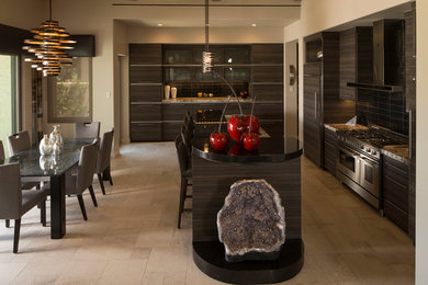 Inspiration for a mid-sized transitional galley ceramic tile eat-in kitchen remodel in Los Angeles with a single-bowl sink, flat-panel cabinets, dark wood cabinets, solid surface countertops, brown backsplash, stone slab backsplash, stainless steel appliances and an island