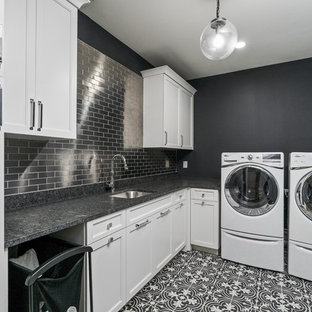 Foto de cuarto de lavado en L, tradicional renovado, con fregadero bajoencimera, armarios con rebordes decorativos, puertas de armario blancas, paredes negras, lavadora y secadora juntas, suelo negro y encimeras negras