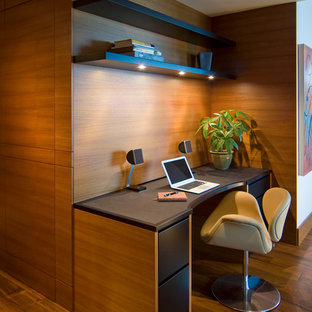 This is an example of a medium sized modern home office and library in San Francisco with medium hardwood flooring and a built-in desk.