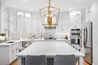 Immagine di un cucina con isola centrale con paraspruzzi grigio, paraspruzzi con piastrelle diamantate, elettrodomestici in acciaio inossidabile e top bianco