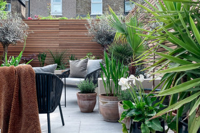 This is an example of a large modern courtyard patio in London with fencing.