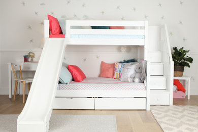 Modelo de dormitorio infantil romántico de tamaño medio con paredes grises, suelo de madera clara, suelo blanco y papel pintado