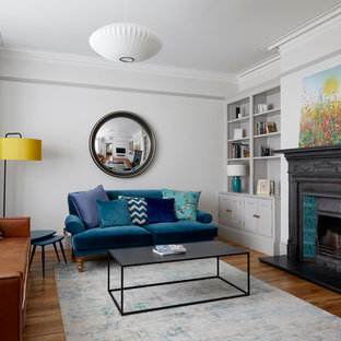 Transitional medium tone wood floor family room photo in London with gray walls and a standard fireplace