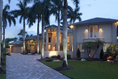 Design ideas for a large tropical two-storey stucco beige house exterior in Miami with a hip roof and a tile roof.