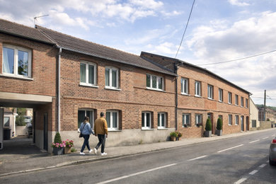 Cette image montre un façade d'immeuble urbain en brique de taille moyenne avec un toit à deux pans, un toit en tuile et un toit rouge.