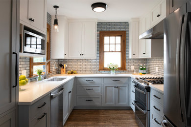 Idéer för att renovera ett litet amerikanskt vit vitt u-kök, med en undermonterad diskho, luckor med infälld panel, blå skåp, bänkskiva i kvarts, vitt stänkskydd, stänkskydd i keramik, rostfria vitvaror, mellanmörkt trägolv och brunt golv