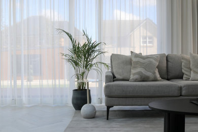 Inspiration for a large modern open plan kitchen in Edinburgh with flat-panel cabinets, grey cabinets, composite countertops, black appliances, vinyl flooring, an island, grey floors, grey worktops and feature lighting.