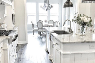 Example of a mid-sized cottage dark wood floor and brown floor eat-in kitchen design in Phoenix with an undermount sink, shaker cabinets, white cabinets, marble countertops, stainless steel appliances, an island and gray countertops