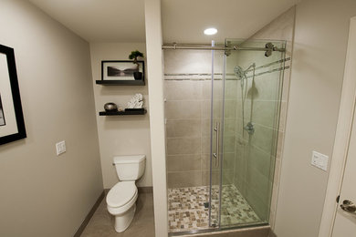 Mid-sized trendy 3/4 gray tile and porcelain tile porcelain tile alcove shower photo in Other with raised-panel cabinets, white cabinets, a two-piece toilet, beige walls, an integrated sink and solid surface countertops
