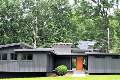 Photo of a mid-sized midcentury grey house exterior in Charlotte with wood siding and a flat roof.