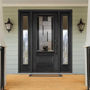 Foto på en eklektisk ingång och ytterdörr, med gröna väggar, ljust trägolv, en enkeldörr och en svart dörr