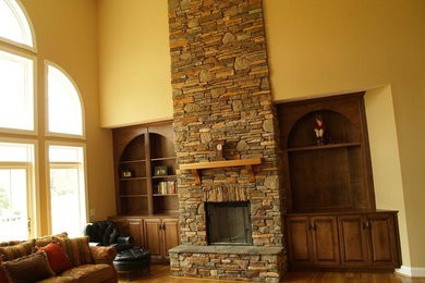 Example of a medium tone wood floor living room design in Other with yellow walls, a standard fireplace and a stone fireplace