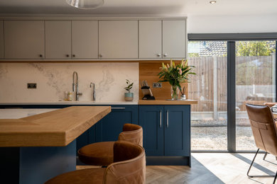 Inspiration for a large modern u-shaped open plan kitchen in Essex with shaker cabinets, blue cabinets, quartz worktops, white splashback, engineered quartz splashback, integrated appliances, an island and white worktops.