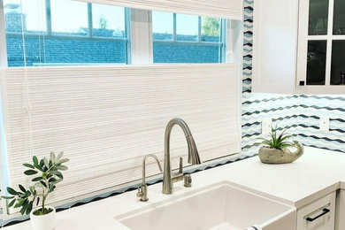 Large beach style l-shaped laminate floor, brown floor and shiplap ceiling eat-in kitchen photo in Los Angeles with shaker cabinets, white cabinets, quartz countertops, blue backsplash, stainless steel appliances, an island and white countertops