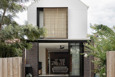 Photo of a mid-sized contemporary two-storey white house exterior in Sydney with concrete fiberboard siding, a gable roof, a metal roof and a white roof.