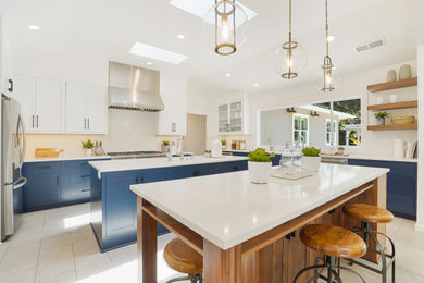 Inspiration for a large transitional u-shaped ceramic tile, white floor and vaulted ceiling eat-in kitchen remodel in San Francisco with an undermount sink, beaded inset cabinets, white cabinets, quartzite countertops, white backsplash, stone slab backsplash, stainless steel appliances, two islands and white countertops