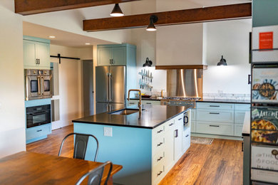 Imagen de cocina abierta con armarios estilo shaker, puertas de armario azules, encimera de esteatita y una isla