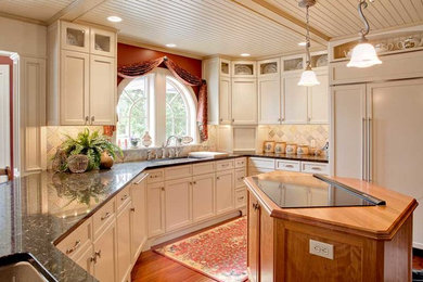 Inspiration for a large timeless u-shaped dark wood floor eat-in kitchen remodel in Philadelphia with an undermount sink, shaker cabinets, white cabinets, granite countertops, beige backsplash, stone tile backsplash, paneled appliances and a peninsula