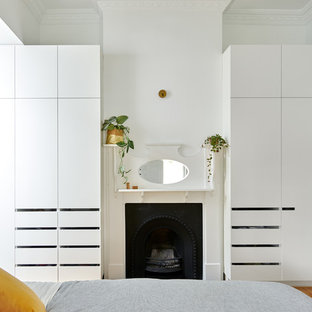 Kleines Modernes Hauptschlafzimmer mit weißer Wandfarbe, Kamin, Kaminumrandung aus Holz, braunem Boden und braunem Holzboden in Melbourne