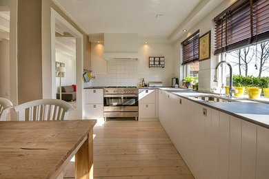 Idéer för ett mellanstort modernt grå kök, med en rustik diskho, skåp i shakerstil, vita skåp, laminatbänkskiva, grått stänkskydd, stänkskydd i keramik, rostfria vitvaror, vinylgolv och beiget golv