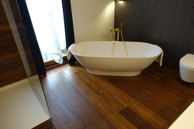 Mittelgroße Moderne Fliesenlose Dusche mit freistehender Badewanne, bodengleicher Dusche, Wandtoilette, braunem Holzboden, Aufsatzwaschbecken, braunem Boden, offener Dusche, Einzelwaschbecken und schwebendem Waschtisch in Nürnberg