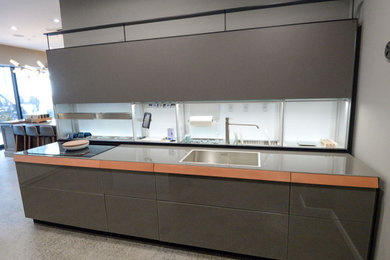 Example of a mid-sized minimalist galley kitchen design in New York with gray cabinets, stainless steel appliances, no island and gray countertops
