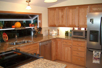 Example of a classic u-shaped light wood floor kitchen design in Portland with light wood cabinets, beige backsplash, stainless steel appliances and no island