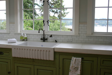 Design ideas for an expansive transitional open plan kitchen in Seattle with a farmhouse sink, raised-panel cabinets, distressed cabinets, concrete benchtops, glass tile splashback, white appliances, light hardwood floors and with island.