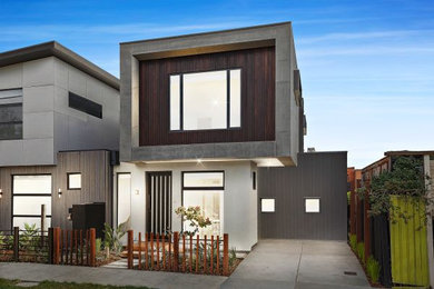 Inspiration for a mid-sized modern two-storey concrete townhouse exterior in Melbourne with a flat roof, a metal roof and board and batten siding.