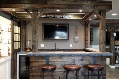 This is an example of a large arts and crafts u-shaped seated home bar in Minneapolis with medium wood cabinets, concrete benchtops, brown splashback, timber splashback, laminate floors and brown floor.