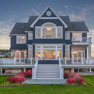 На фото: двухэтажный, большой фасад частного дома синего цвета в классическом стиле с облицовкой из дерева, двускатной крышей и крышей из гибкой черепицы с
