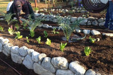 Design ideas for a mid-sized rustic drought-tolerant and full sun front yard river rock raised garden bed in Los Angeles.