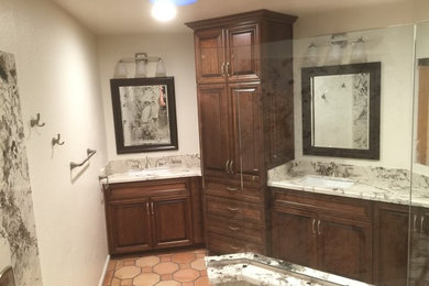 Bathroom - large rustic master black and white tile and stone slab terra-cotta tile and brown floor bathroom idea in Phoenix with raised-panel cabinets, brown cabinets, a two-piece toilet, white walls, a drop-in sink, granite countertops and white countertops