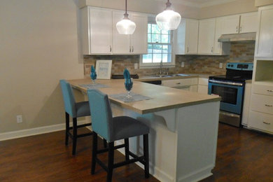 Kitchen - mid-sized traditional u-shaped laminate floor kitchen idea in Nashville with a double-bowl sink, recessed-panel cabinets, white cabinets, beige backsplash, ceramic backsplash and stainless steel appliances
