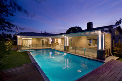 This is an example of a large modern backyard lap pool in Los Angeles with a hot tub and decking.