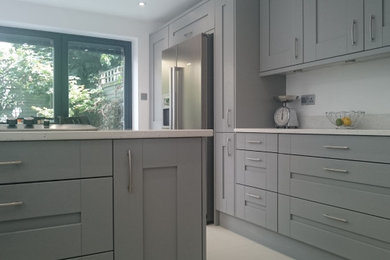 Eat-in kitchen - contemporary porcelain tile eat-in kitchen idea in London with shaker cabinets, quartzite countertops, stainless steel appliances and white countertops