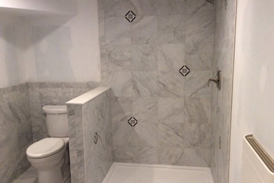 This is an example of a mid-sized mediterranean master bathroom in New York with marble benchtops, a corner shower, a one-piece toilet, gray tile, porcelain tile, white walls and porcelain floors.