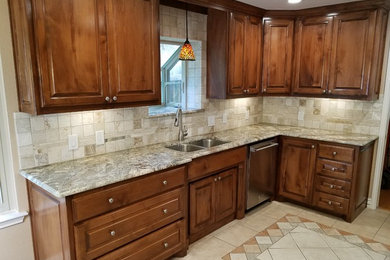Photo of a mid-sized traditional galley eat-in kitchen in Dallas with an undermount sink, raised-panel cabinets, medium wood cabinets, granite benchtops, beige splashback, stone tile splashback, stainless steel appliances, ceramic floors, no island and beige floor.