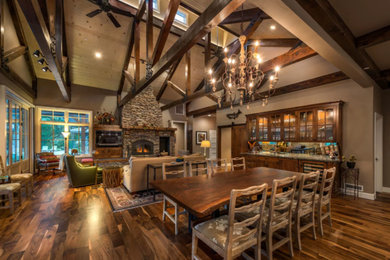 Example of a large farmhouse dark wood floor and brown floor great room design in Other with brown walls, a standard fireplace and a stone fireplace