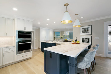 Large transitional l-shaped light wood floor and white floor eat-in kitchen photo in San Francisco with an undermount sink, shaker cabinets, blue cabinets, quartz countertops, white backsplash, marble backsplash, stainless steel appliances, an island and white countertops